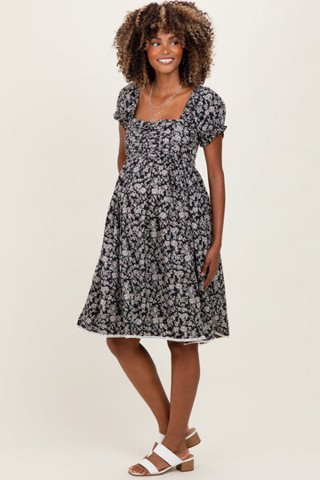 woman wearing a black floral maternity dress with puff sleeves and a baby bump visible