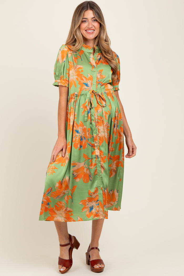 woman wearing a green floral maternity dress with short sleeves and a tie waist, showcasing her baby bump