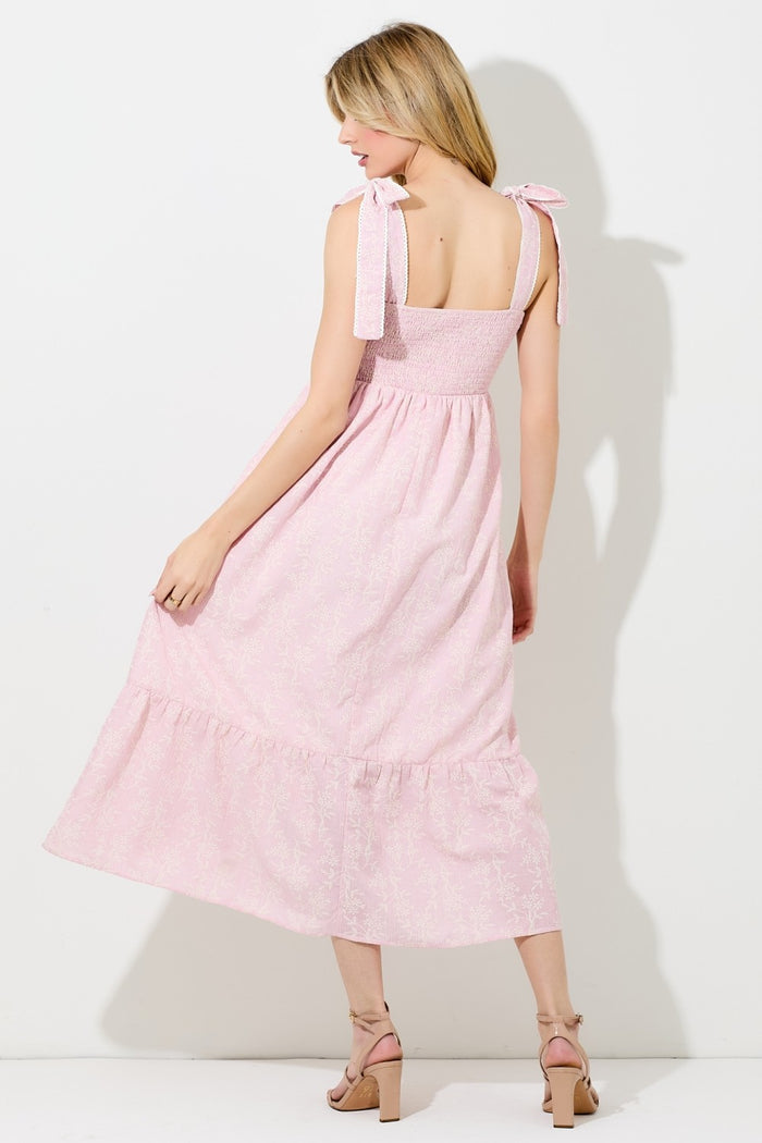 woman wearing a pink floral tie strap maxi dress, showing the back and ruffled hem detail