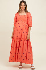 woman wearing a coral maternity maxidress with floral embroidery and puff sleeves, showcasing her baby bump
