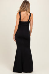 woman wearing a black maternity dress with a fitted silhouette and flared bottom, shown from the back