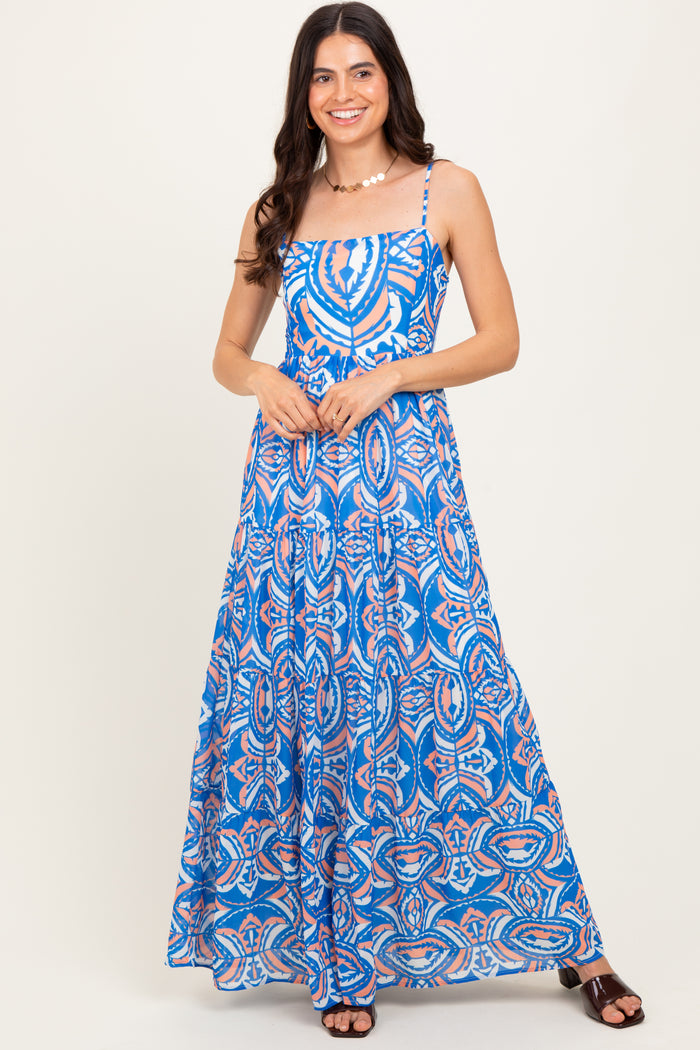 woman wearing a blue maxi dress with a colorful abstract pattern and thin adjustable straps