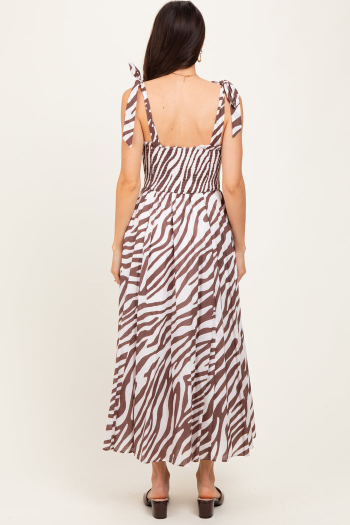 woman wearing a brown and white zebra print maxi dress with adjustable tie straps and a smocked back design