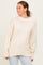 woman wearing a light beige oversized sweater with ribbed cuffs and hem, styled with light wash jeans