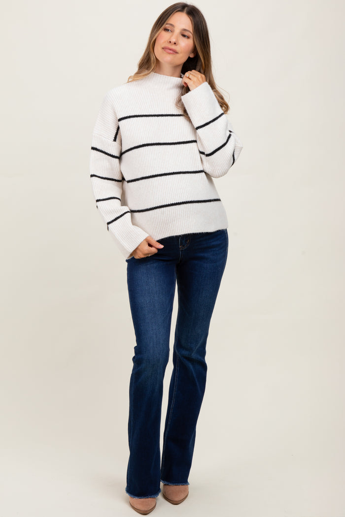 woman wearing a striped maternity sweater with a mock neck and flared jeans, looking stylish and comfortable