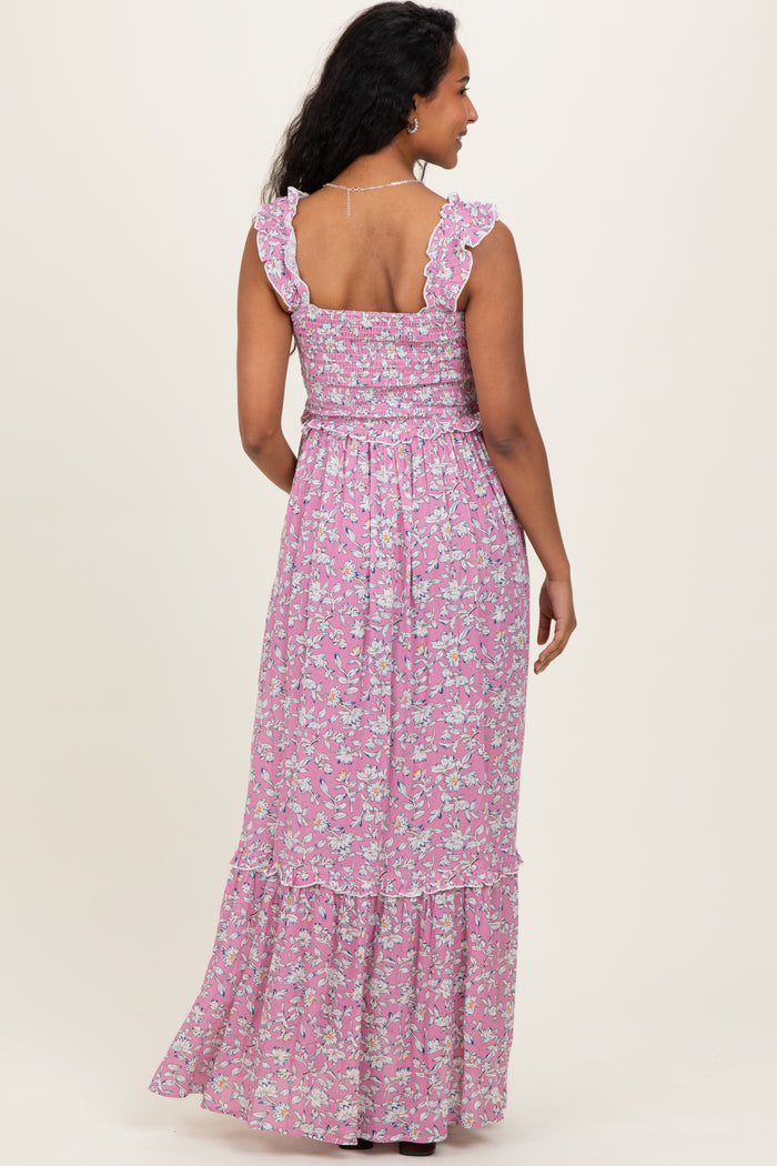 woman wearing a pink floral maternity maxi dress with ruffled straps and a tiered hem, showing her baby bump from the back