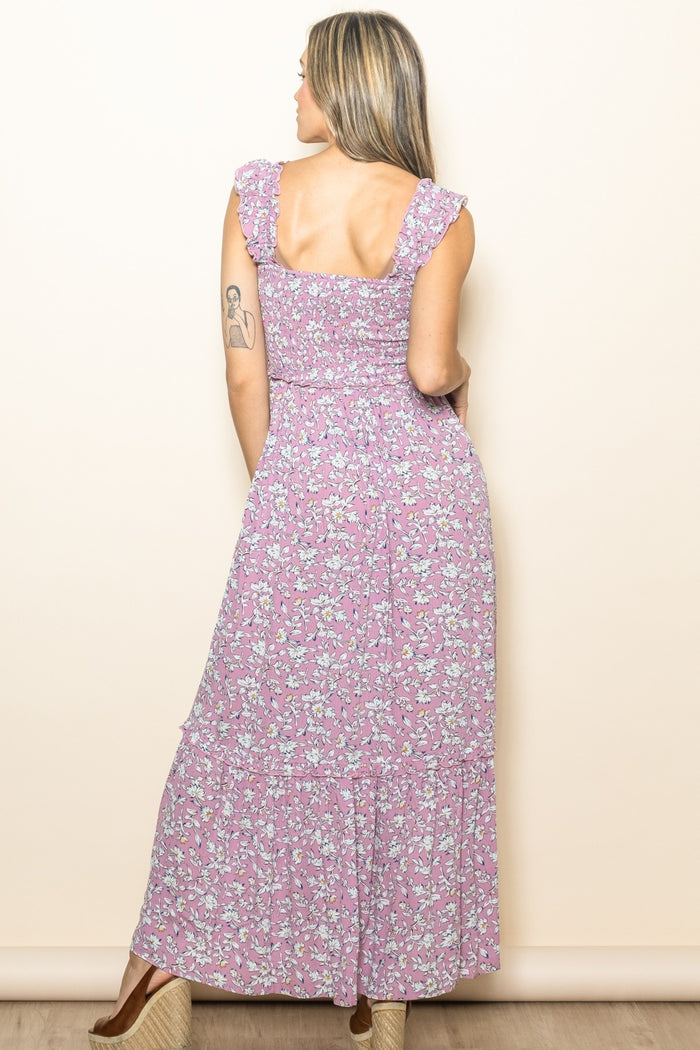 woman wearing a purple floral maxi dress with ruffled sleeves and a smocked bodice, seen from the back
