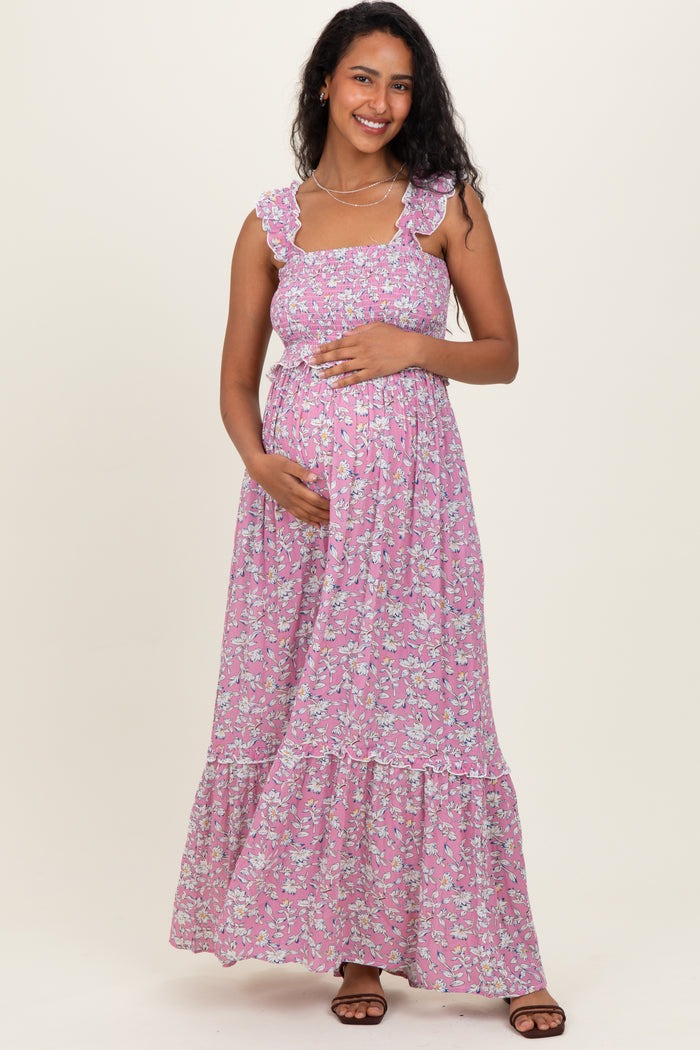 woman wearing a pink floral maternity maxi dress with ruffled straps and holding her baby bump
