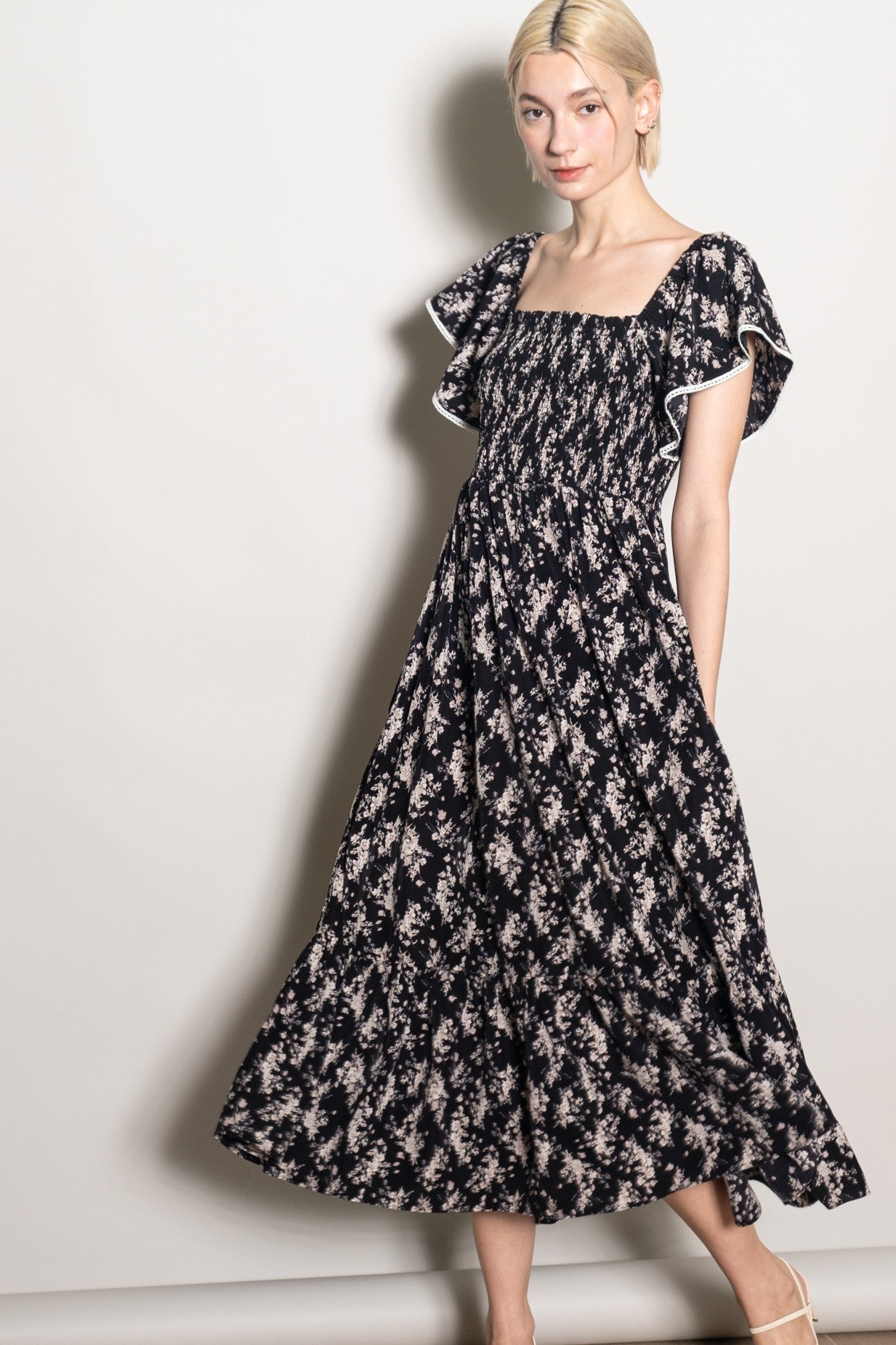 woman wearing a black floral maxi dress with a square neckline and ruffled sleeves