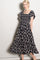woman wearing a black floral maxi dress with a square neckline and ruffled sleeves