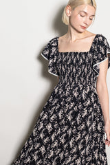 woman wearing a black floral print maxi dress with puff sleeves and a smocked bodice