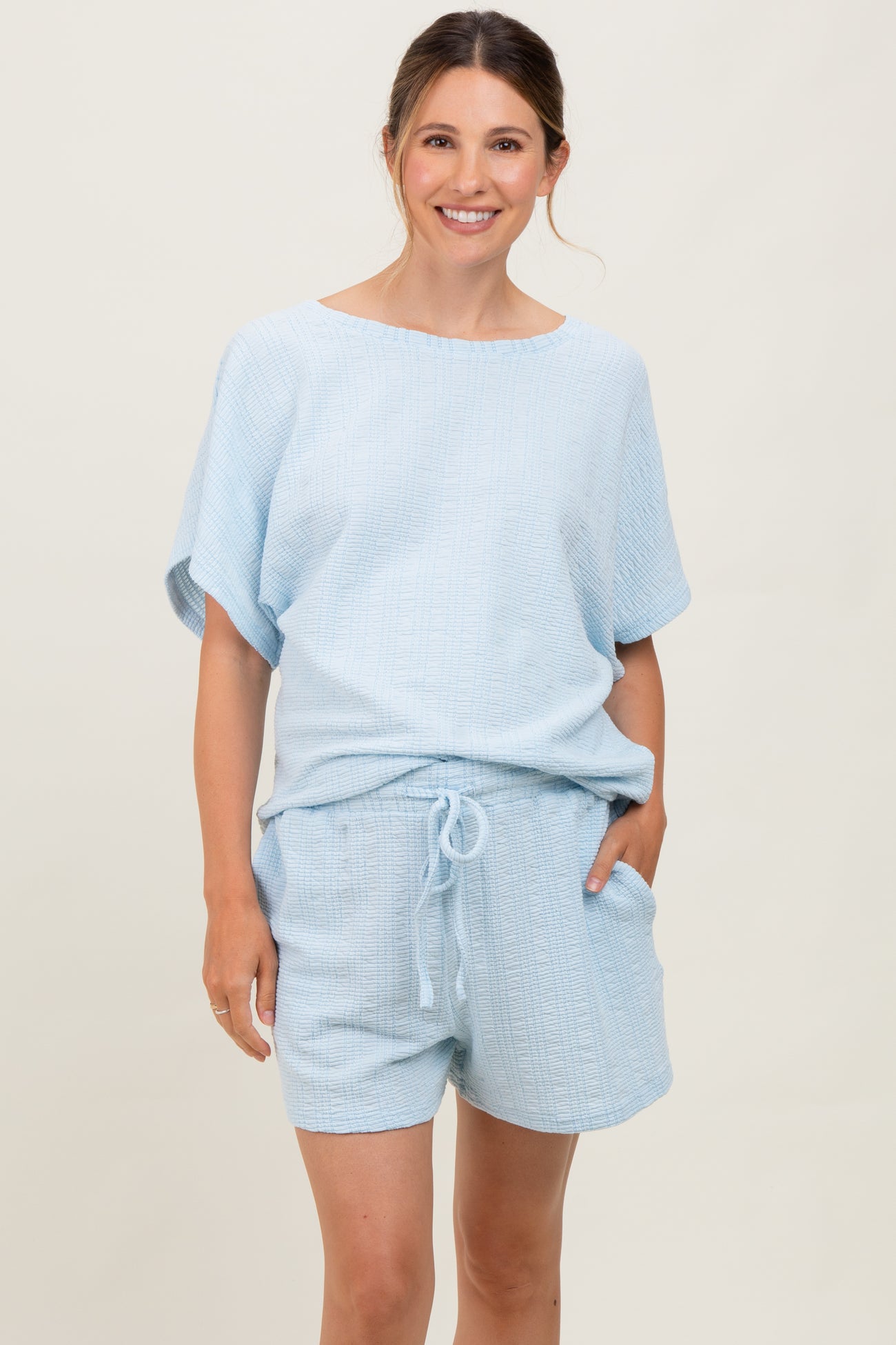 woman wearing a light blue maternity two-piece set with a loose-fitting top and shorts, featuring a textured pattern