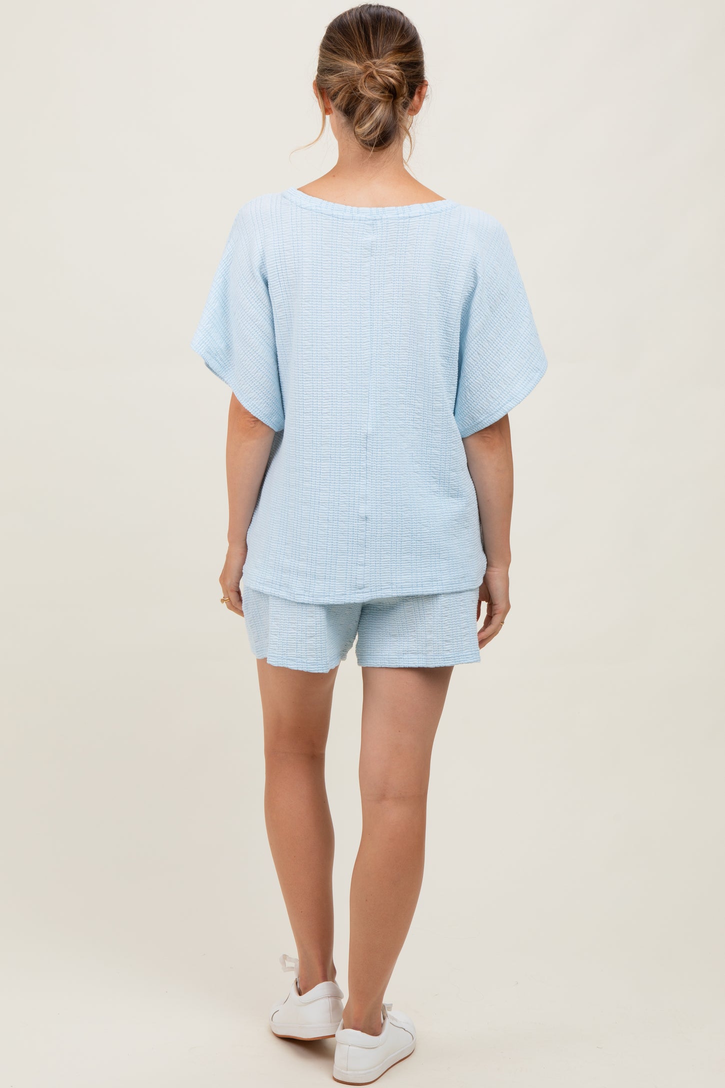 woman wearing a light blue maternity short set with a loose fit and short sleeves from the back