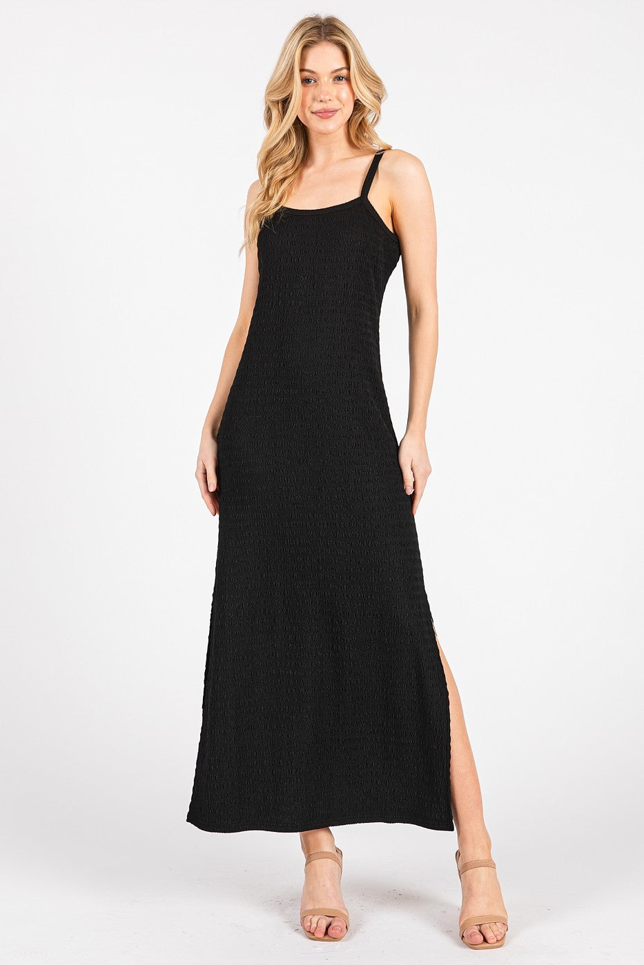 woman wearing a black smocked maxi dress with side slits and thin straps