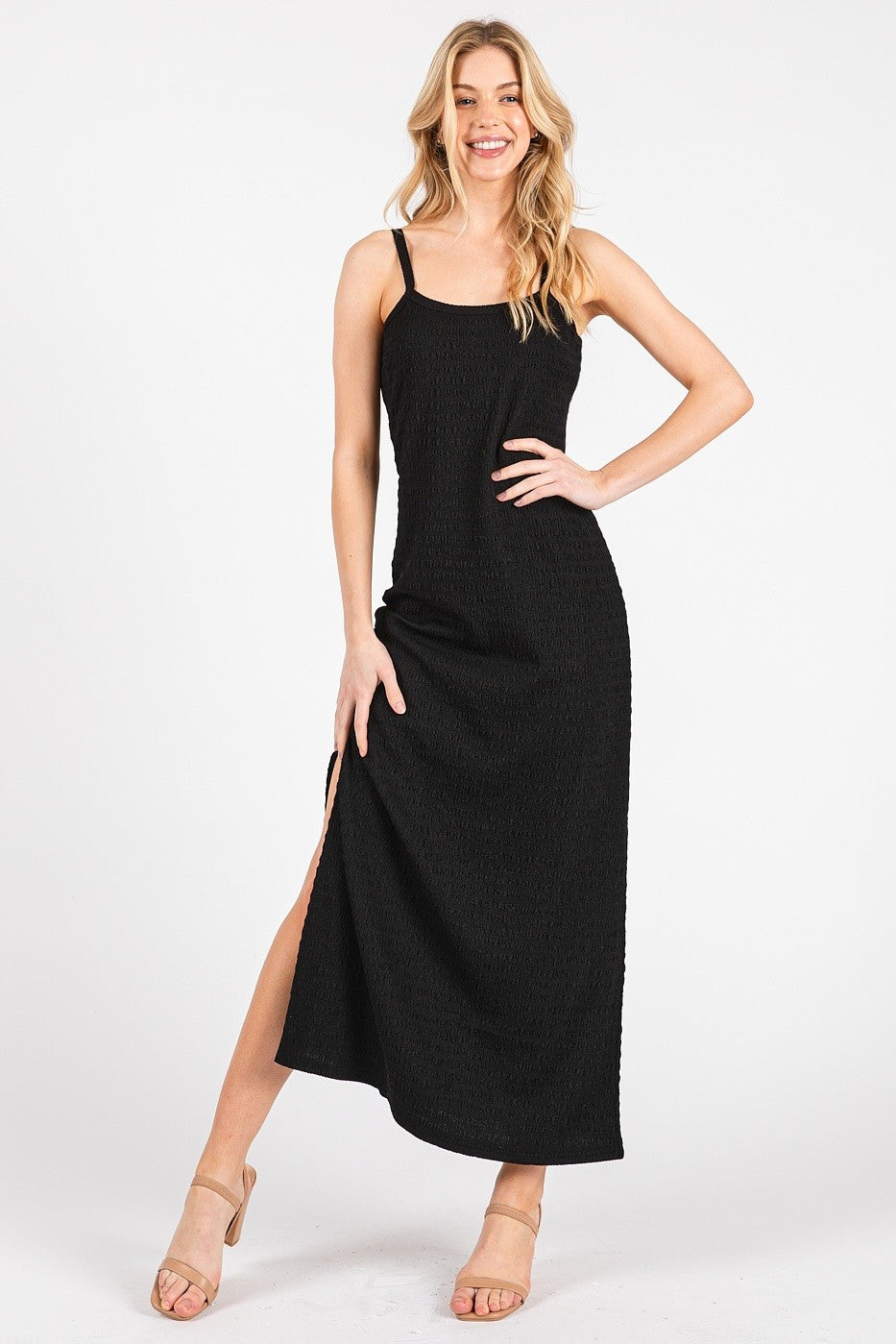 woman wearing a black sleeveless maxi dress with a side slit and a textured finish