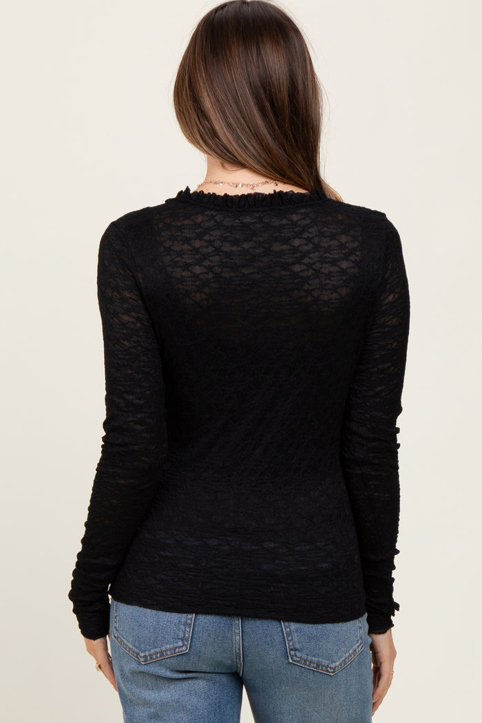 woman wearing a black long sleeve maternity top with textured fabric and ruffled neckline, seen from the back