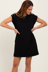 woman wearing a black short sleeve dress with button details on the shoulders and a relaxed fit