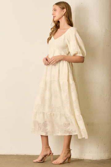 woman wearing a cream colored midi dress with puff sleeves and a tiered skirt