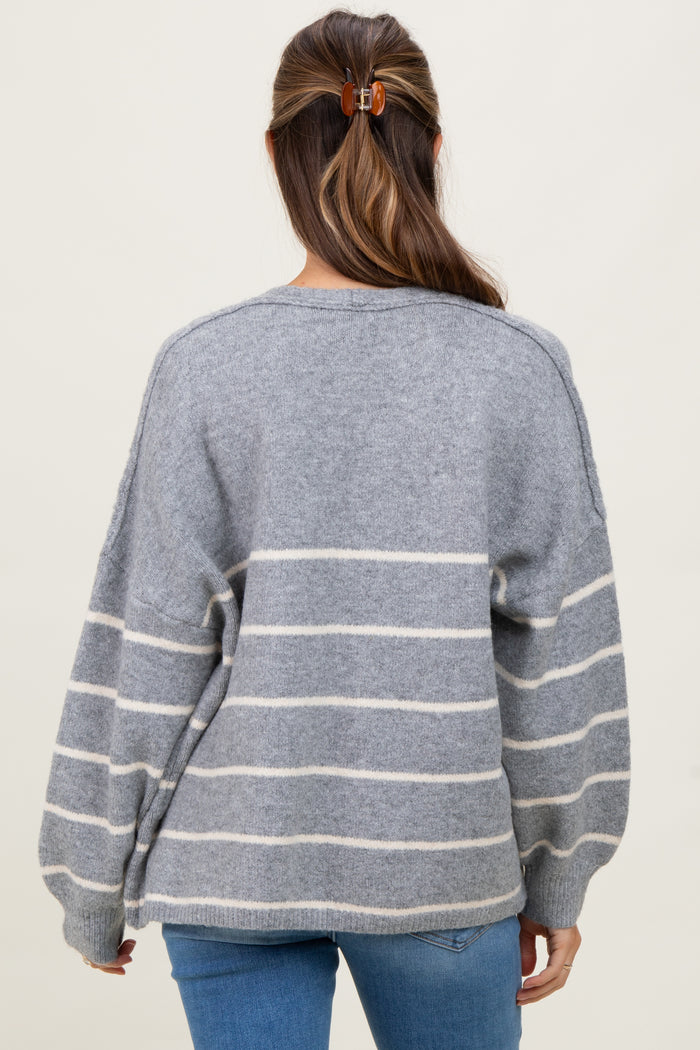 woman wearing a gray striped oversized maternity sweater from the back with balloon sleeves and light blue jeans