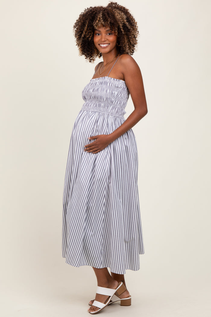 woman wearing a striped maternity maxi dress with smocked bodice and a visible baby bump