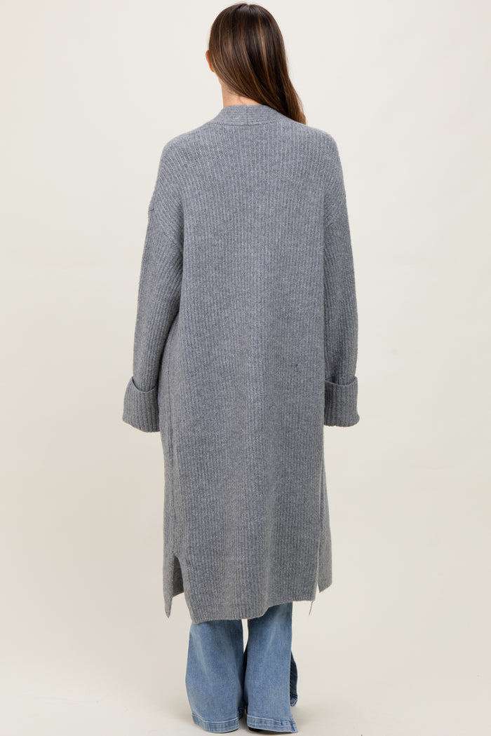 woman wearing a long grey maternity cardigan with ribbed texture and side slits, viewed from the back