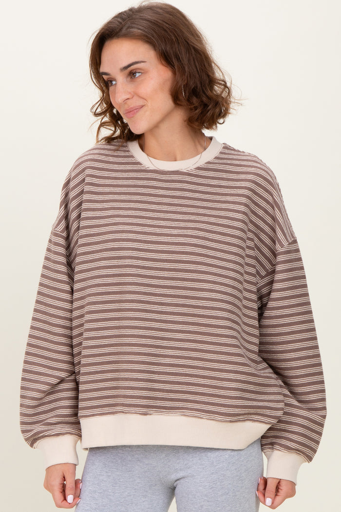 woman wearing a brown striped oversized sweatshirt with beige cuffs and hem