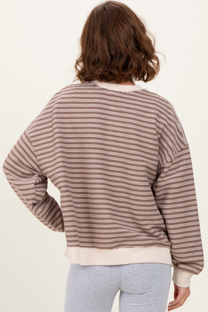 woman wearing a brown and cream striped oversized sweater, view of the back with relaxed fit and ribbed hem