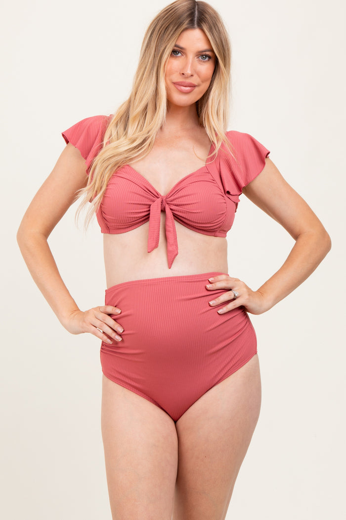 woman wearing a rose pink maternity bikini with ruffled sleeves and high-waisted bottoms, showcasing her baby bump