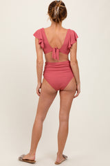 woman wearing a pink ribbed bikini with flutter sleeves and high-waisted bottoms, seen from the back