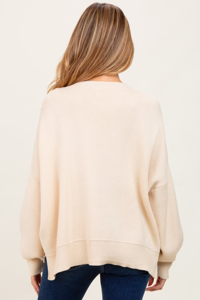 woman wearing a beige oversized maternity sweater with a loose fit, showing the back view