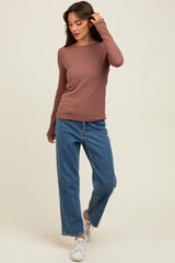 woman wearing a brown long sleeve top paired with high-waisted blue wide leg jeans and white sneakers