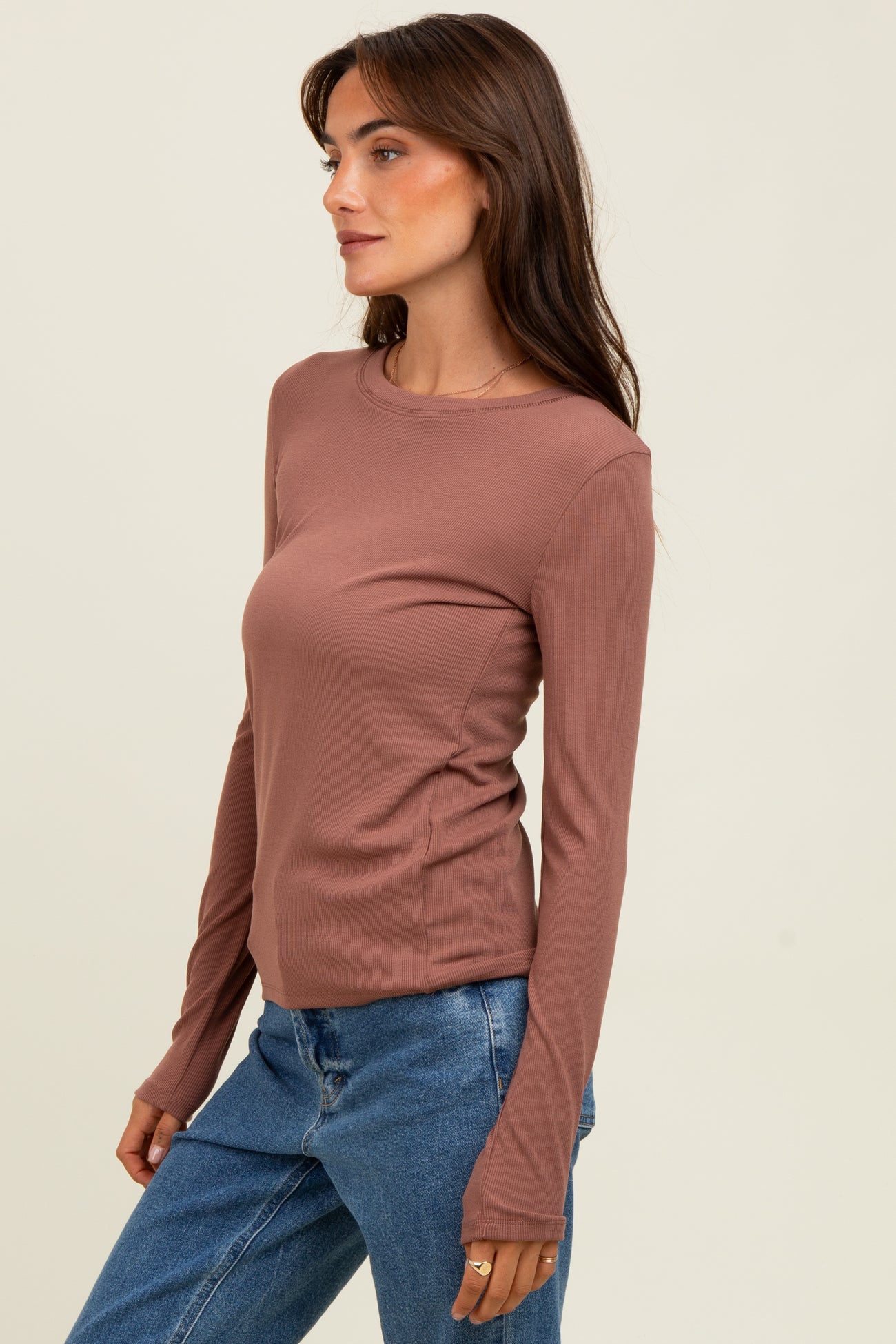 woman wearing a rust long sleeve ribbed top with a fitted style and round neckline, paired with blue jeans