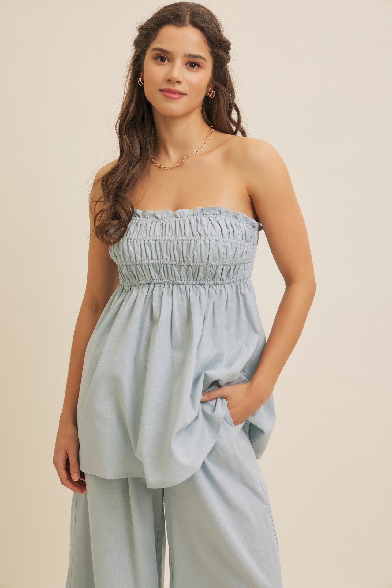 woman wearing a light blue strapless top with gathered details and loose fit, paired with matching wide-leg pants
