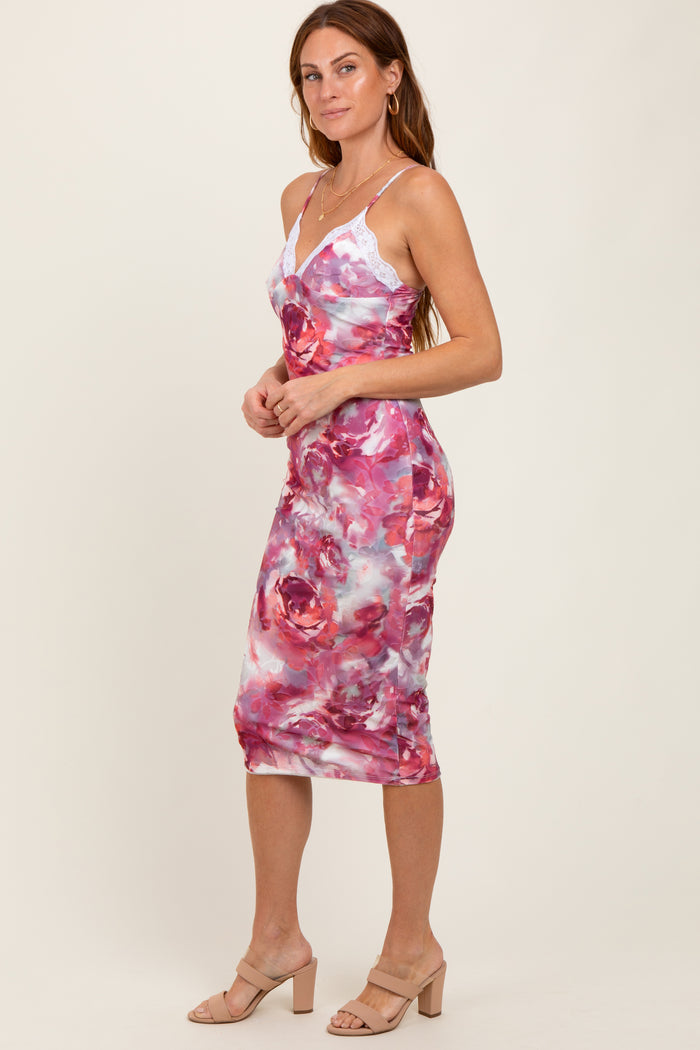 woman wearing a pink and white floral midi dress with lace straps and a fitted silhouette