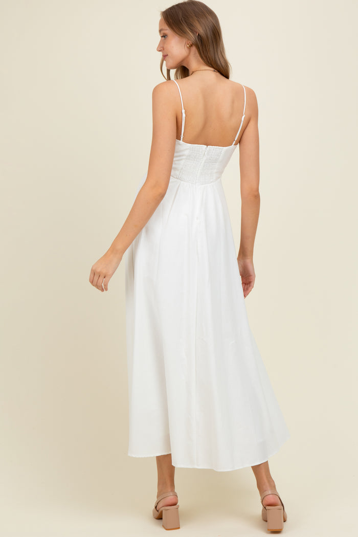 woman wearing a white maternity maxi dress with a smocked bodice and spaghetti straps, showing her back
