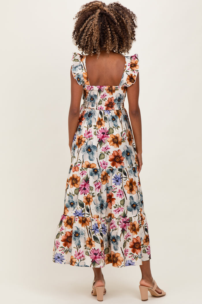 woman wearing a floral print maternity maxi dress with ruffled straps and a smocked bodice, showing a baby bump