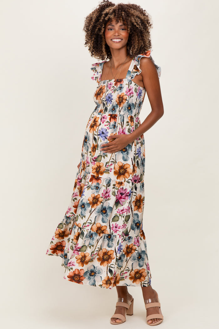 woman wearing a floral maternity maxi dress with ruffled straps and holding her baby bump