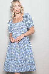 woman wearing a blue and white gingham puff sleeve mini dress with a smocked bodice and tiered skirt