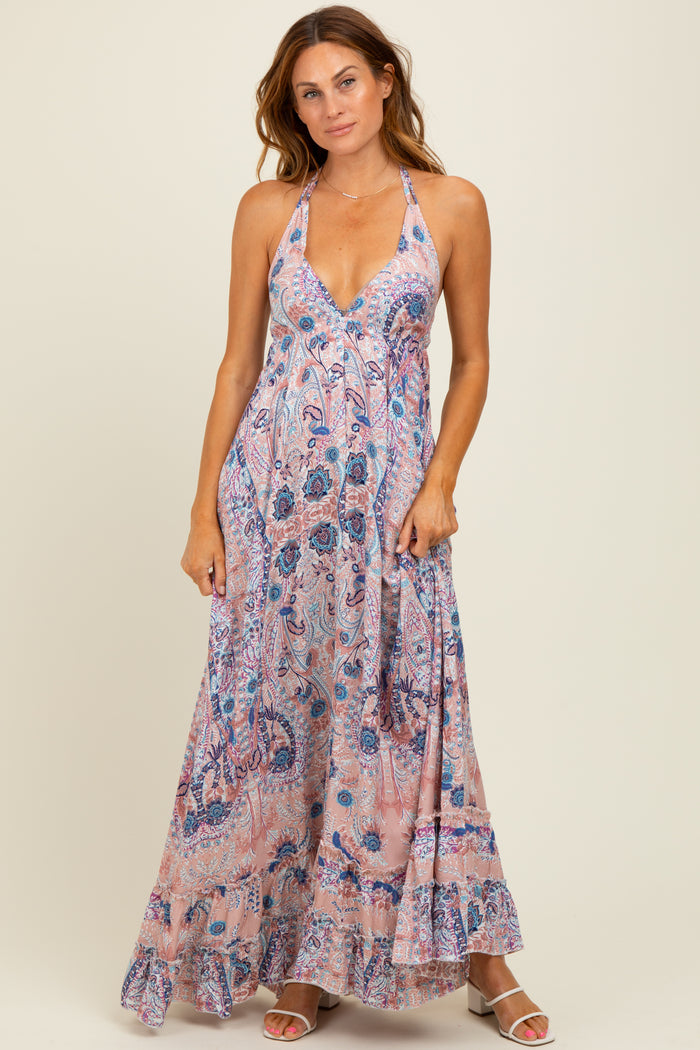 woman wearing a flowy pink paisley maxi dress with a halter neckline and ruffled hem