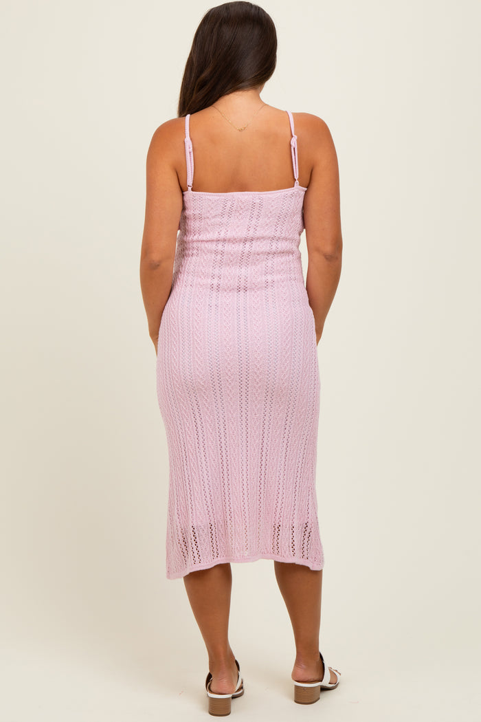 woman wearing a light pink crochet maternity dress with a form-fitting silhouette and adjustable straps