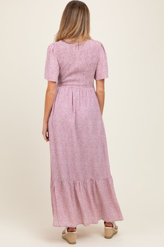 woman in a long pink floral maternity dress with puff sleeves and a tiered skirt, showing the back view