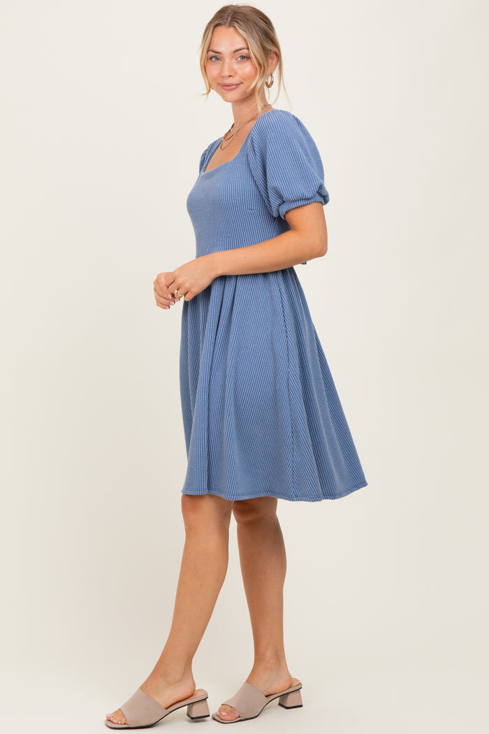 woman wearing a blue short sleeve dress with a square neckline and a flared skirt, styled with beige sandals