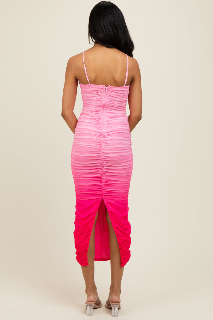 woman wearing a pink ombre fitted dress with ruching and a back slit, showing the back view