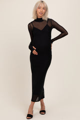 woman wearing a black maternity dress with sheer long sleeves and a fitted silhouette showcasing her baby bump