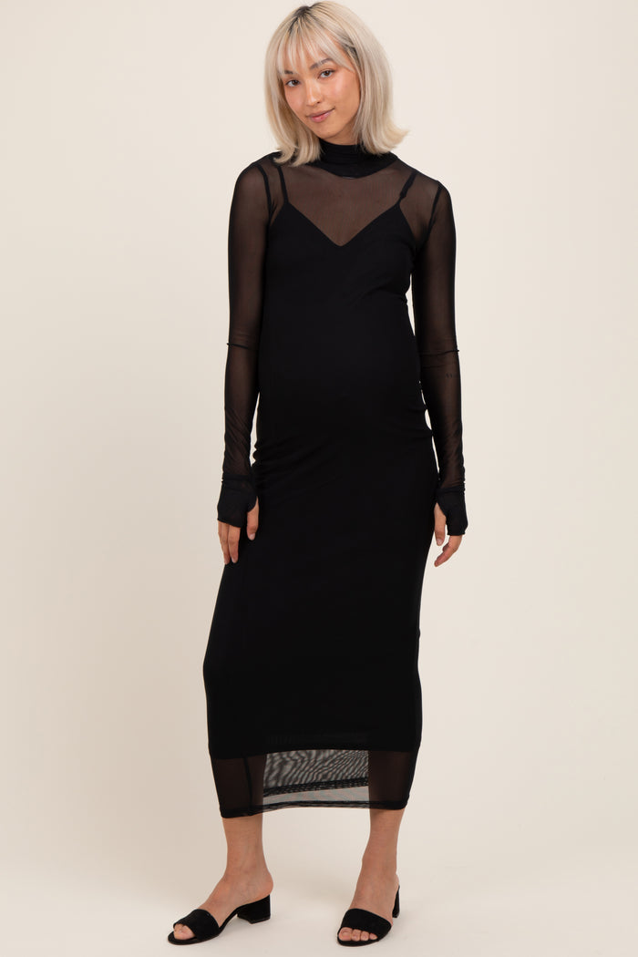 woman wearing a black maternity dress with sheer long sleeves and a fitted silhouette, showing her baby bump