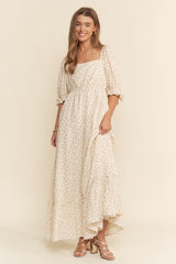woman wearing a floral print maxi dress with puff sleeves and a square neckline, standing in a light background