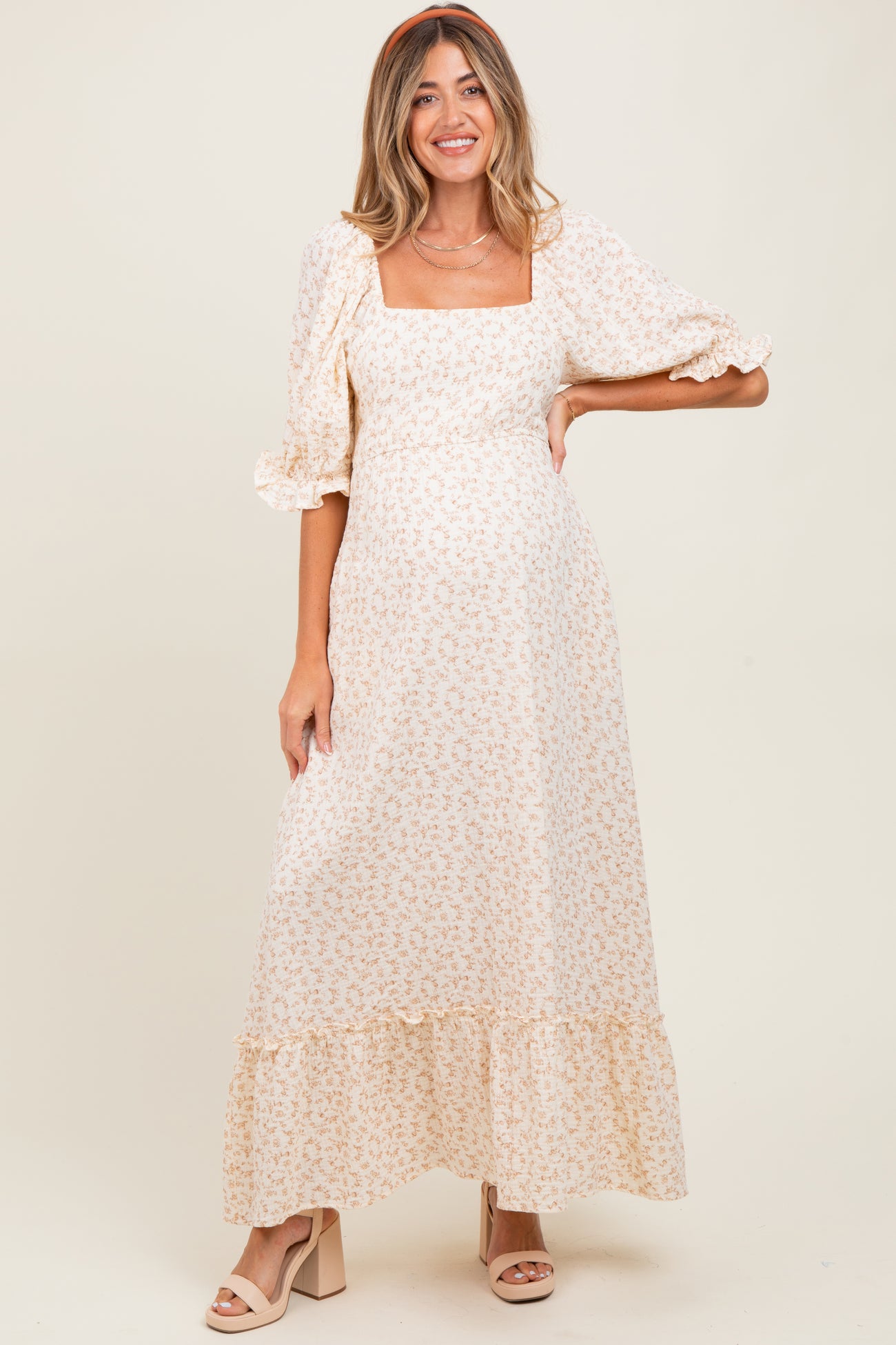 woman wearing a cream floral maternity maxi dress with puff sleeves and a square neckline, showcasing her baby bump