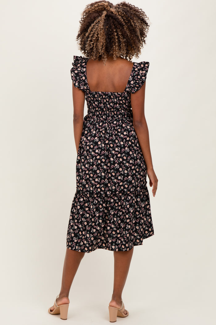 woman wearing a black floral print maternity dress with ruffled sleeves and a flared hem, showing her baby bump from behind