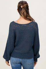 woman wearing a navy blue open-knit maternity sweater with a loose fit and bell sleeves