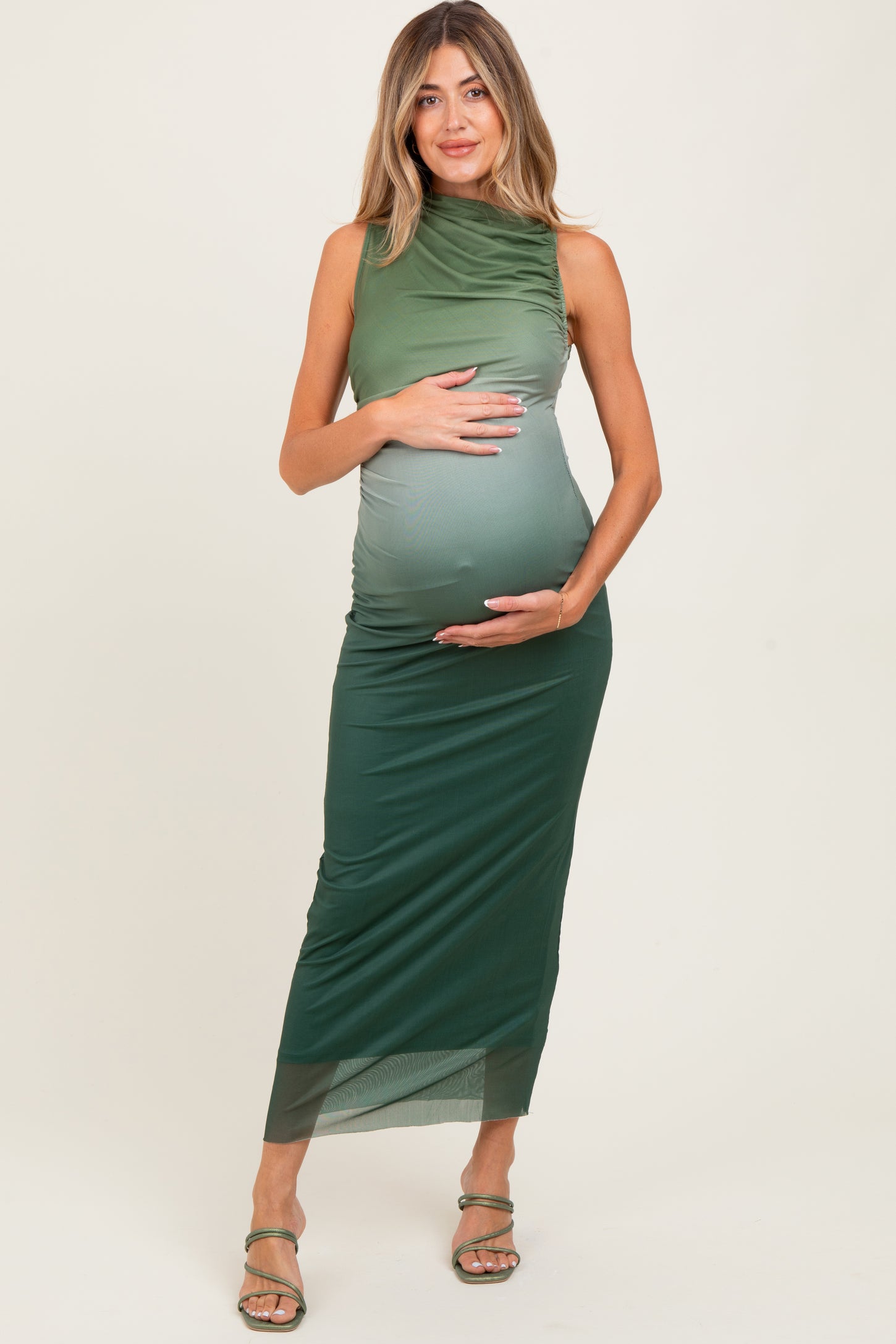 woman wearing a green ombre maternity dress with a fitted silhouette, showing her baby bump and standing confidently